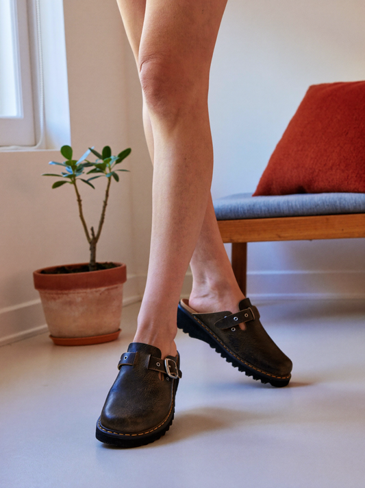 Model wearing dark brown leather clog slippers