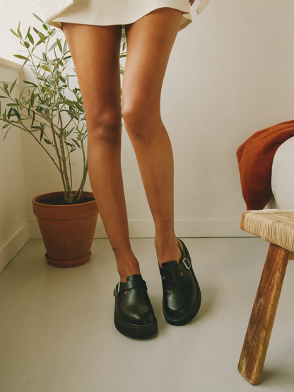 Model wearing black leather clog slippers