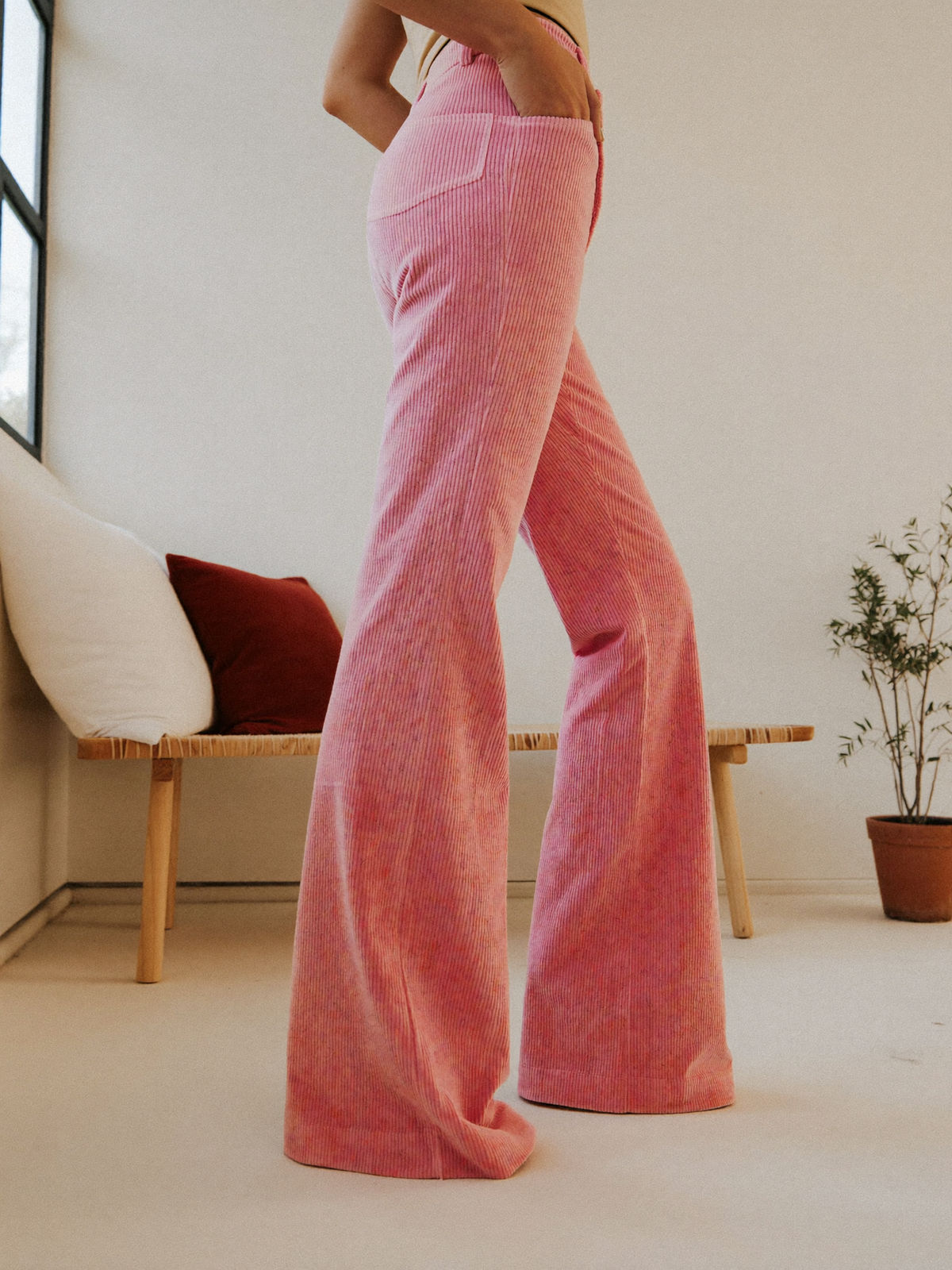 Model wearing pink flared trousers, posing