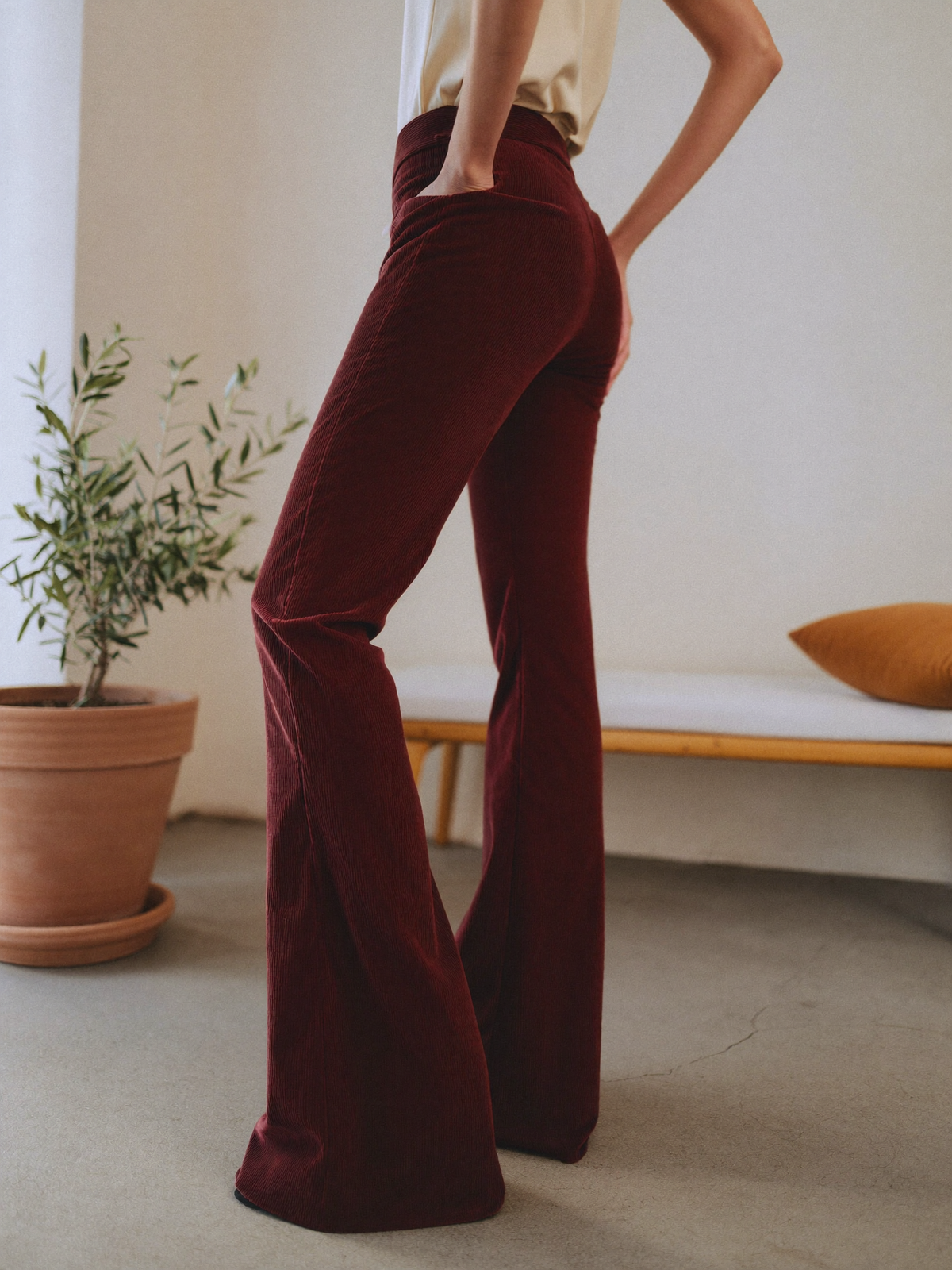 Model wearing burgundy flared trousers, posing